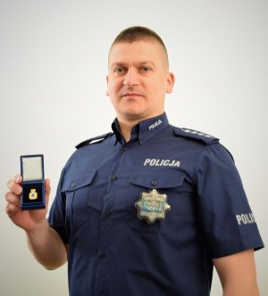 Policjant prezentuje Złotą Odznakę „Za opiekę nad zabytkami”
