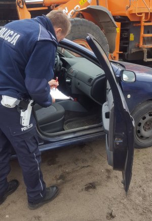 policjant wykonuje oględziny samochodu