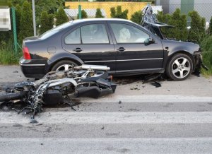 Zdjęcie przedstawia skutki wypadku - uszkodzony motocykl i samochód