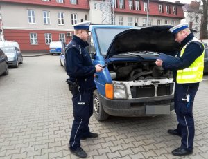 Policjanci robią oględziny zabezpieczonego samochodu