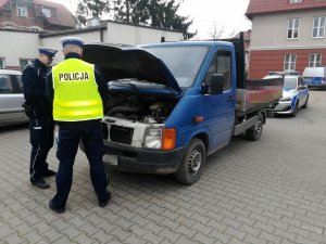 Policjanci robią oględziny zabezpieczonego samochodu
