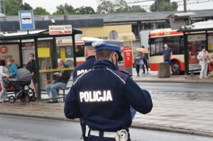 Policjant prowadzi kontrolę na przystanku autobusowym.