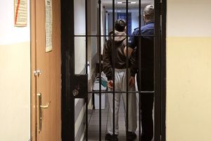 policjant prowadzi zatrzymanego do pomieszczenia dla osób zatrzymanego