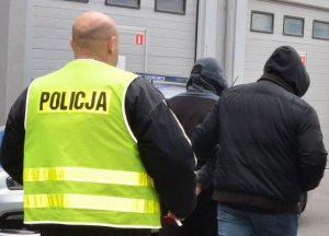 Policjanci prowadzą zatrzymanego mężczyznę