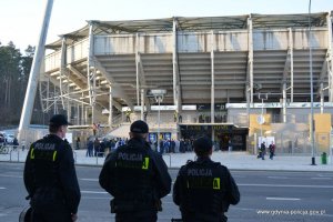 Policjanci w trakcie zabezpieczenia meczu, w tle kibice