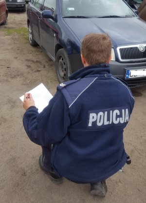 policjant wykonuje oględziny samochodu