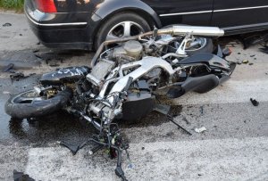 Zdjęcie przedstawia skutki wypadku - uszkodzony motocykl i samochód