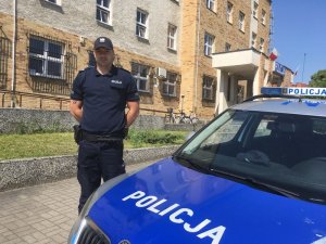 Policjant stoi przy radiowozie