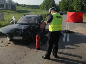 Policjant przeprowadza oględziny pojazdu i motocykla na miejscu zdarzenia