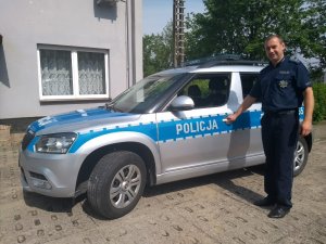 Policjant - dzielnicowy stoi przy radiowozie