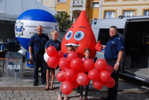 Policjanci wraz z maskotką przy radiowozie