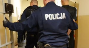 Policjanci prowadzą zatrzymanego