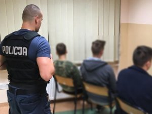 Policjant pilnuje zatrzymanych sprawców pobicia