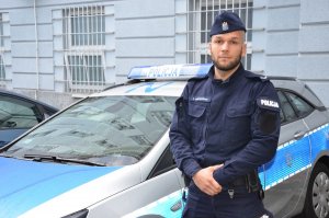 Policjant stoi przy radiowozie