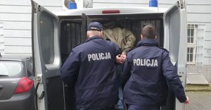 Policjanci prowadzą zatrzymanego do radiowozu