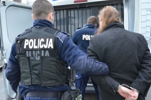 Policjanci prowadzą zatrzymanego do radiowozu