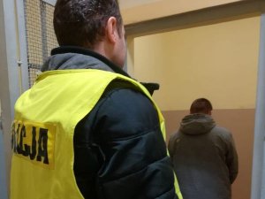 Policjant prowadzi zatrzymanego do celi