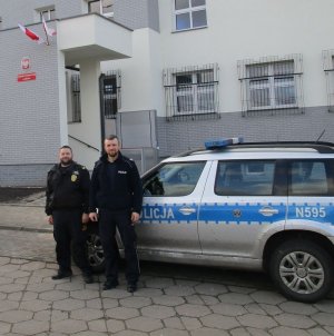 Policjanci stoją przy radiowozie