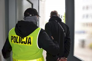 Policjant prowadzi zatrzymanego