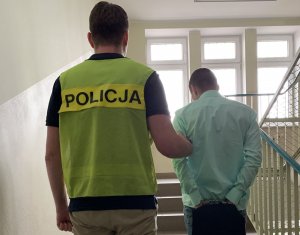 Policjant prowadzi zatrzymanego