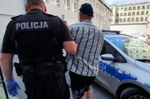 Policjant prowadzi zatrzymanego.