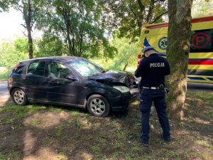 Policjant stoi przy rozbitym samochodzie