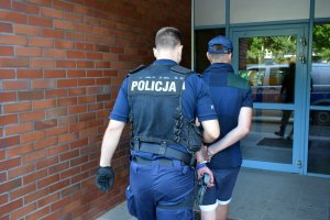 Policjant prowadzi zatrzymanego