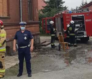 Policjant stoi koło budynku