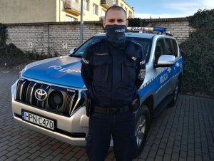 Policjant stoi przy radiowozie