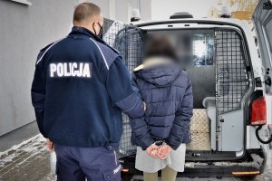 Policjant prowadzi kobietę do radiowozu