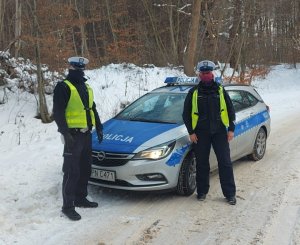 Policjanci stoją przy radiowozie