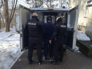 Policjanci prowadzą zatrzymanego do radiowozu