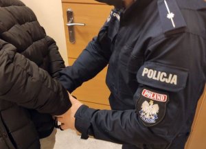 policjant zakłada kajdanki zatrzymanemu