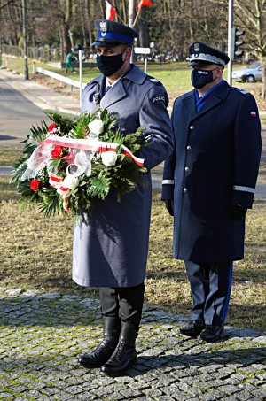 Na zdjęciu Komendant Wojewódzki Policji w Gdańsku wraz z funkcjonariuszem OPP KWP w Gdańsku trzymającym wiązankę przed pomnikiem.