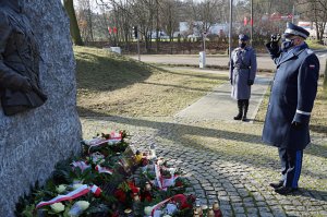 Komendant Wojewódzki Policji w Gdańsku oddaje honory przed pomnikiem po złożeniu kwiatów.