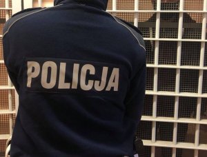 policjant zamyka zatrzymanego w celi