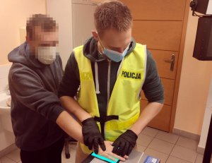 policjant pobiera odciski palców