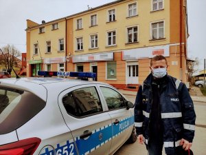 policjant stoi obok radiowozu