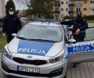 policjanci stoją przy radiowozie