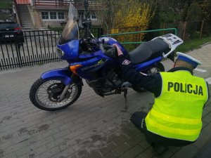 policjant kuca przy motocyklu