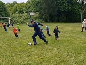 policjant gra w piłkę nożną z dziećmi na boisku