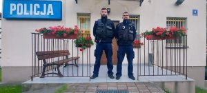 dwóch umundurowanych policjantów stoi przed budynkiem jednostki Policji