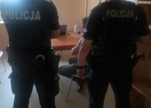 Policjant doprowadza zatrzymanego