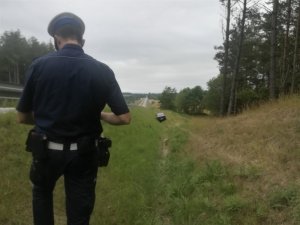 policjant patrzy na stojący w rowie samochód