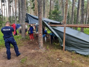 policjant w trakcie kontroli obozu harcerskiego w lesie