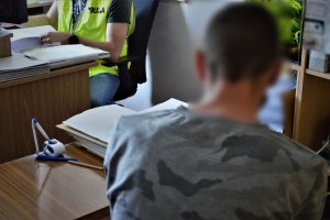 zatrzymany mężczyzna przy biurku z policjantem