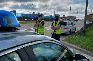 policjanci stoją przy jezdni, kontrolują kierowców