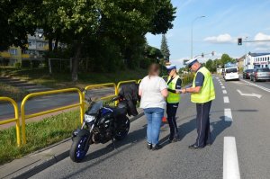 policjanci ruchu drogowego, wykonują oględziny na miejscu wypadku, rozmawiają ze świadkami