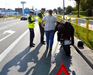 policjanci ruchu drogowego, wykonują oględziny na miejscu wypadku, rozmawiają ze świadkami