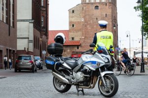 policjanci ruchu drogowego stoją przy  radiowozach i motocyklu